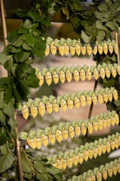 some green leaves and yellow stickers hanging from a tree with trees in the background