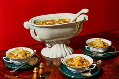 there is a bowl of soup on the table with other bowls and spoons next to it