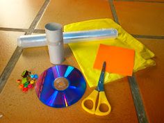 a table topped with cds and scissors on top of a wooden floor next to plastic bags