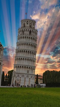 the leaning tower of pisa at sunset with beams of light in the sky above it