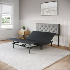 a bed sitting on top of a wooden floor next to a white rug and window