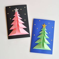 two paper christmas trees sitting next to each other