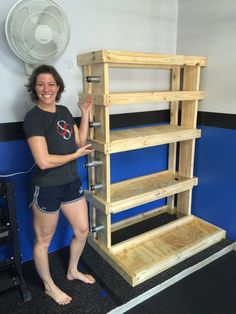 a woman standing next to a wooden shelf