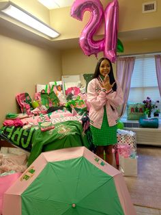 a woman standing next to a bed with pink and green decorations