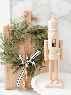 a wooden toy standing next to a christmas wreath and nutcracker ornament