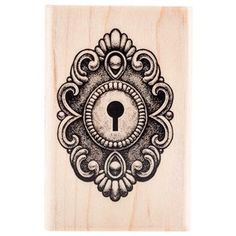 a wooden stamp with an ornate design and a key on the front, in black ink