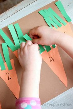 a child is cutting out carrots with green paper