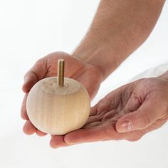 a person holding a wooden object in their hands with a screw sticking out of it