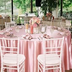 the table is set with pink linens and white chairs for an elegant wedding reception