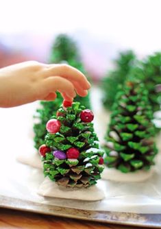 small pine cone trees on a tray with one being hand over the top to another