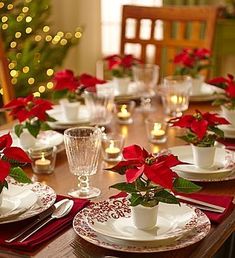 the table is set for christmas dinner with poinsettis in white cups and saucers