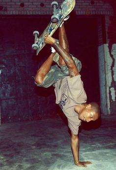 a young man doing a handstand with his skateboard