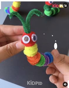 someone is making a caterpillar out of yarn and plastic beads with googly eyes