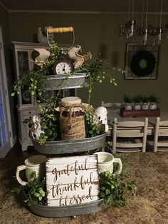 three tiered metal trays with plants and decorations on them, one has a sign that says grateful