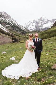 a bride and groom posing for a photo in the mountains