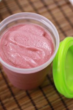 a pink smoothie in a plastic cup with a green lid