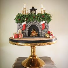 there is a christmas cake on top of a gold plated stand with candles and decorations