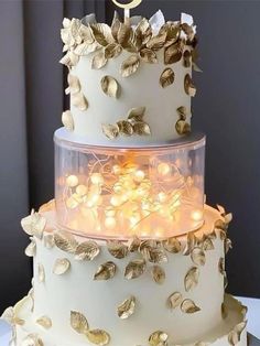 a three tiered cake with gold leaves on it