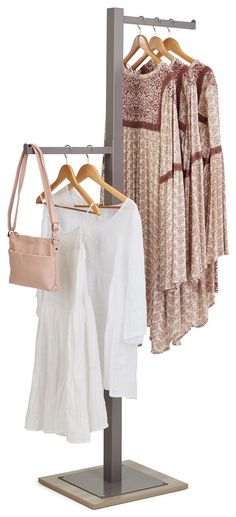 three dresses hanging on a clothes rack with two purses and one handbag in the foreground