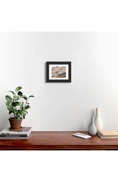 a wooden table topped with a potted plant next to a white wall