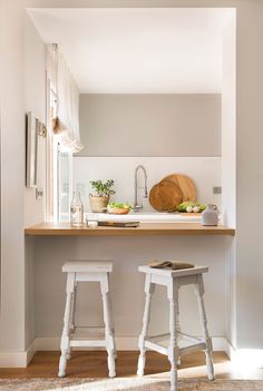 two stools in front of a counter with food on it and a cutting board