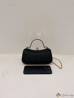 a black purse sitting on top of a table next to a cell phone