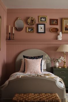 a bedroom with pink walls and pictures on the wall above the bed, along with a green dresser