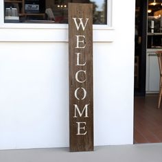 a wooden welcome sign on the outside of a store front door that says, welcome