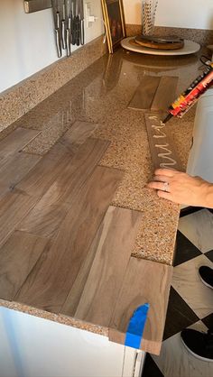 a person is using a knife to cut out the wood for a counter top in a kitchen