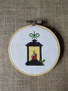 a cross stitched picture of a nativity scene in a small frame on the ground