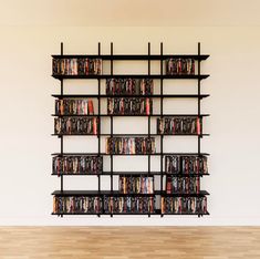 a book shelf filled with lots of books on top of a hard wood floor next to a white wall