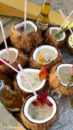 there are many drinks in coconuts on the tray with straws and flowers around them