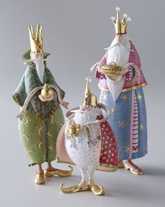 three figurines are standing next to each other with crowns on their heads and holding food in their hands