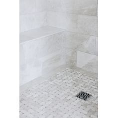 a white tiled shower with a drain in the floor