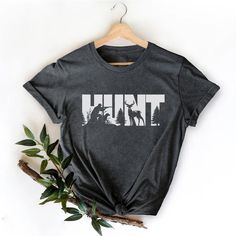 a t - shirt with the word hunt printed on it next to a tree branch