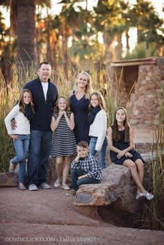 a family posing for a photo in front of some tall grass and palm trees at sunset