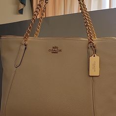 Handbag New With Tag Purchased From Coach Store In Ga. Never Used. Handbag Has Pebbled Grain Leather Gold Hardware Chain And Leather Strap Roomy Handbag A Classic Cream Bags With Metal Hardware For Everyday Use, Coach Gold Shoulder Bag With Metal Hardware, Gold Coach Shoulder Bag With Metal Hardware, Everyday Cream Bag With Chain Strap, Coach Leather Bag With Chain Detail, Coach Gold Shoulder Bag With Chain Strap, Chic Coach Bag With Chain Detail, Chic Coach Bag With Chain, Cream Leather Bag With Chain Strap