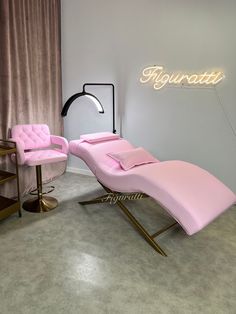 a pink chaise lounge chair sitting in front of a neon sign