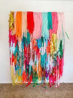 colorful streamers are hanging on the wall in front of a carpeted floor and white wall