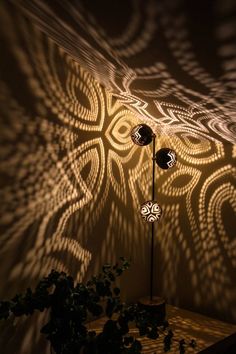 the shadow of two lamps is cast on the wall next to a potted plant