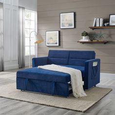 a blue couch sitting on top of a wooden floor next to a white rug and window