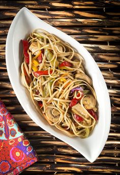 a white plate topped with pasta and veggies on top of a wooden table