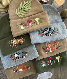 four towels with embroidered animals on them and candles in the background, along with other items