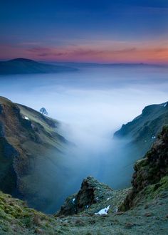 the mountains are covered in fog as the sun sets over them and there is no image to provide a caption for