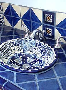 a blue and white sink sitting on top of a bathroom counter next to a faucet