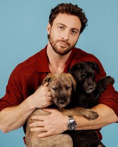 a man holding three puppies in his arms