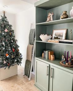 a christmas tree is in the corner of a room with shelves and other decorations on it