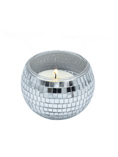 a candle that is sitting on top of a glass bowl filled with silver mosaic tiles