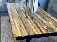 a table made out of wooden planks with two white plates on top and one black metal stand