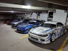 several cars parked in a parking garage with one car painted blue and the other white